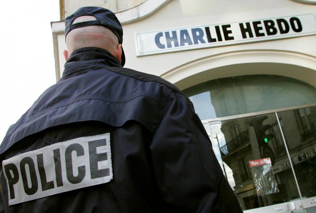 A policeman stands guard outside the French satirical weekly "Charlie Hebdo" in Paris in this February 9, 2006 file photo. At least 10 people were killed in a shooting at the Paris offices of Charlie Hebdo, a satirical newspaper firebombed in the past after publishing cartoons joking about Muslim leaders, French TV channel iTELE reported January 7, 2015 . France Info radio also said police had confirmed a toll of 10 dead and five injured. Reuters had no immediate official confirmation of deaths. Picture taken February 9, 2006. REUTERS/Regis Duvignau/Files (FRANCE - Tags: CRIME LAW MEDIA)